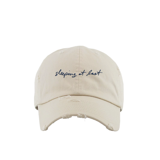 Beige cap with 'sleeping at last' embroidery on a white background