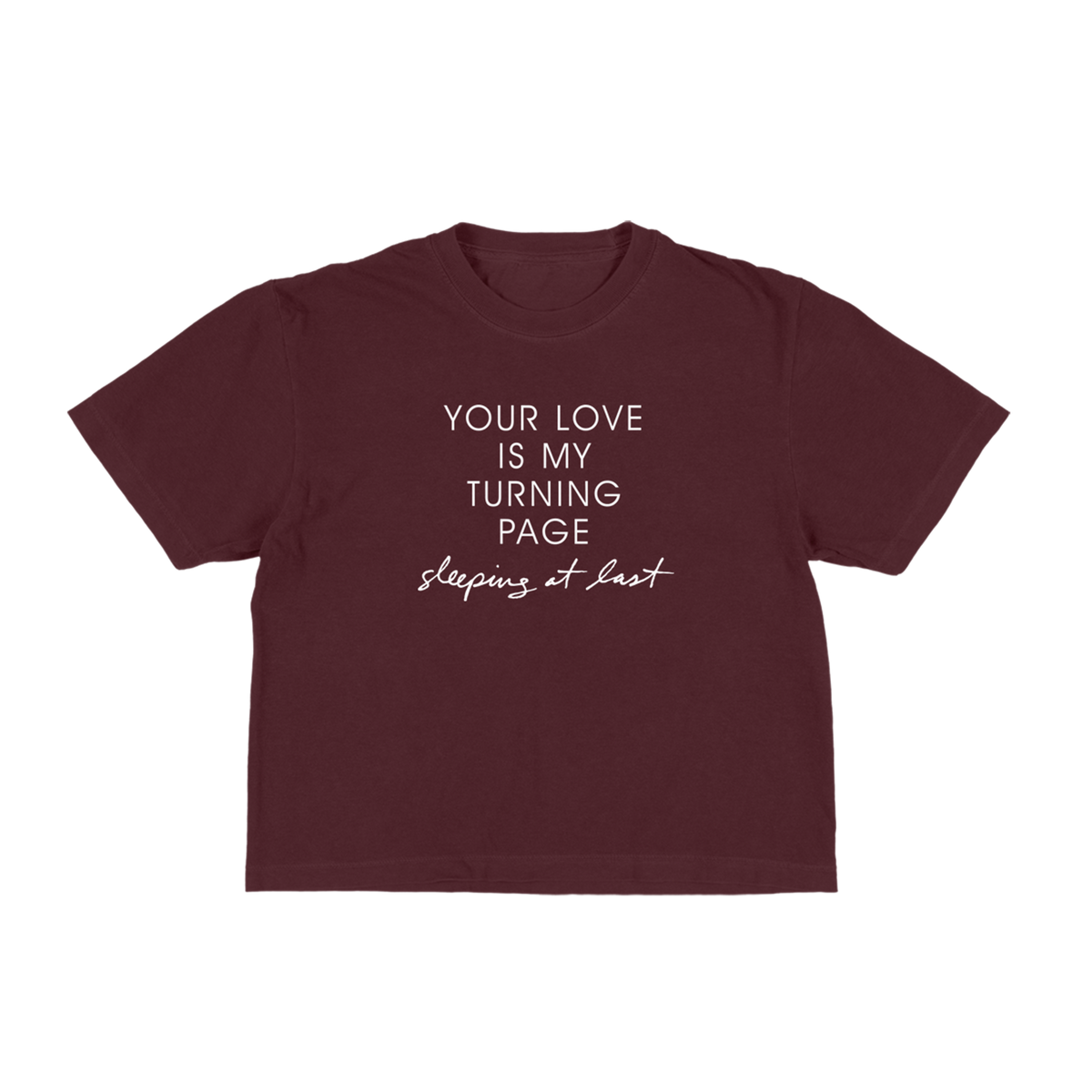 A maroon short-sleeve t-shirt with white printed text on the front reading 'YOUR LOVE IS MY TURNING PAGE sleeping at last'